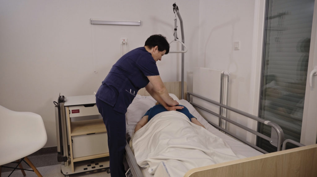 Pielęgniarka udziela pomocy pacjentce na łóżku
