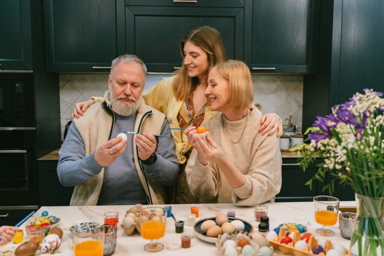 Rodzina malująca pisanki przy stole